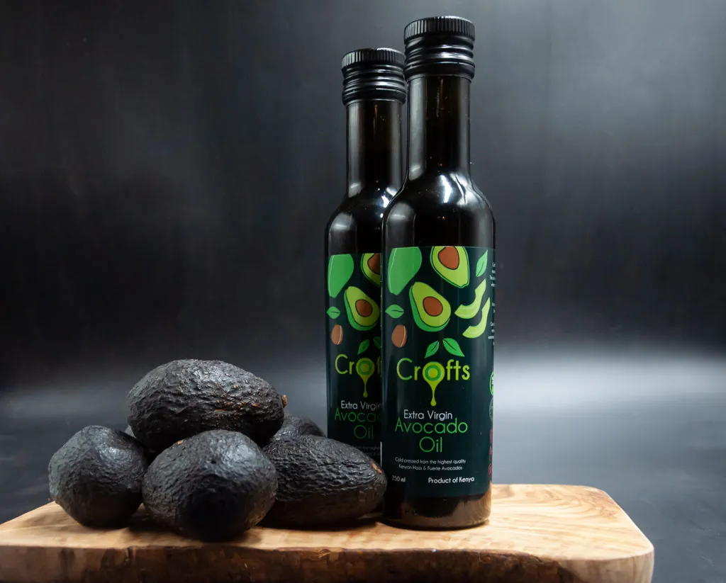 Two 250 ml bottles of Crofts extra virgin avocado oil beside Hass avocados